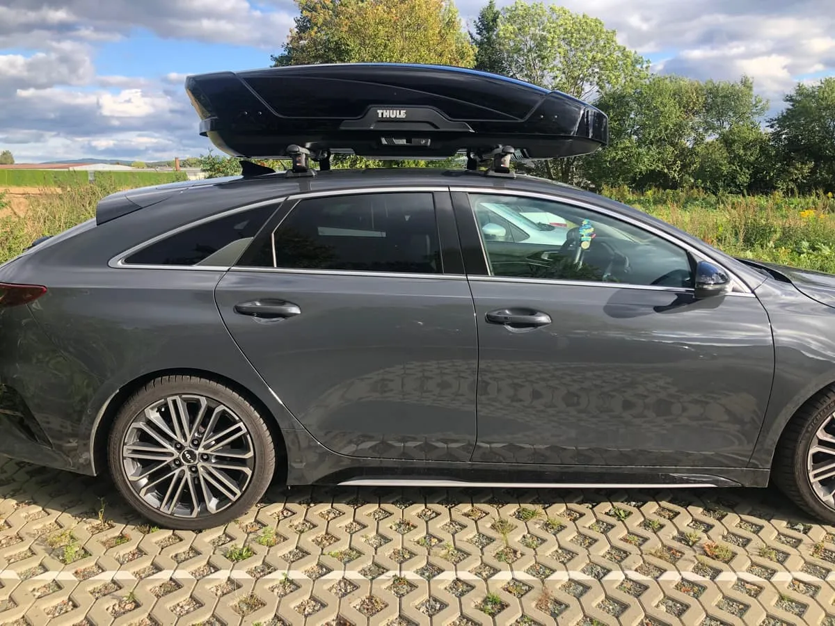 Grauer Kombi mit schwarzer Thule-Dachbox auf dem Dach, Seitenansicht