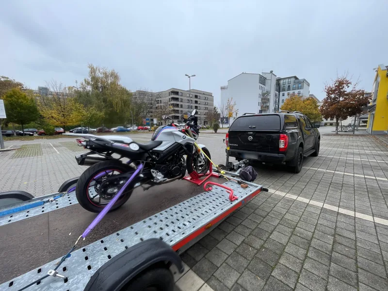 Motorrad auf dem Anhänger, davor der Pickup mit Blick auf die Stadt