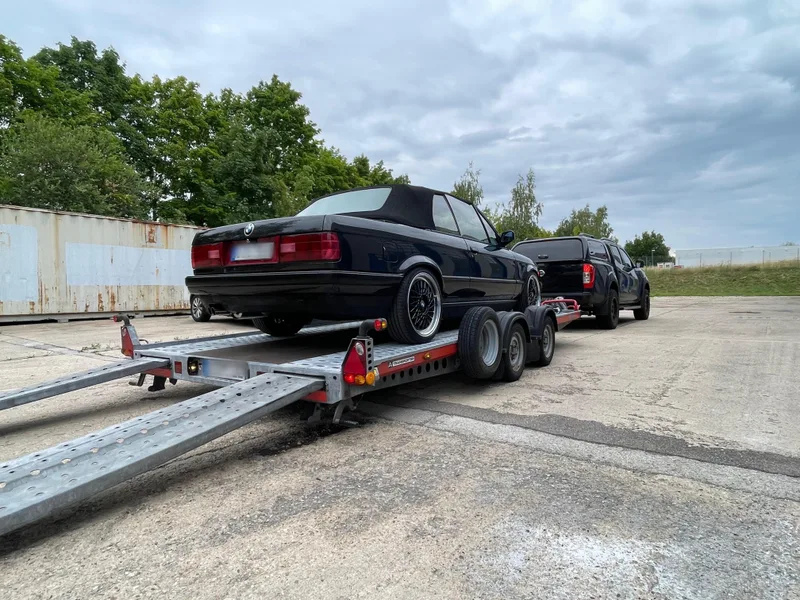 Schwarzes BMW-Cabrio auf dem Anhänger hinter dem Pickup